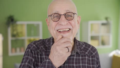 Cheerful-and-funny-old-man-at-home-looking-at-camera-and-laughing.